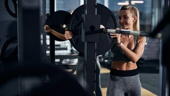 Frau bereitet eine Langhantel im Gym für das Gewichtstraining vor.