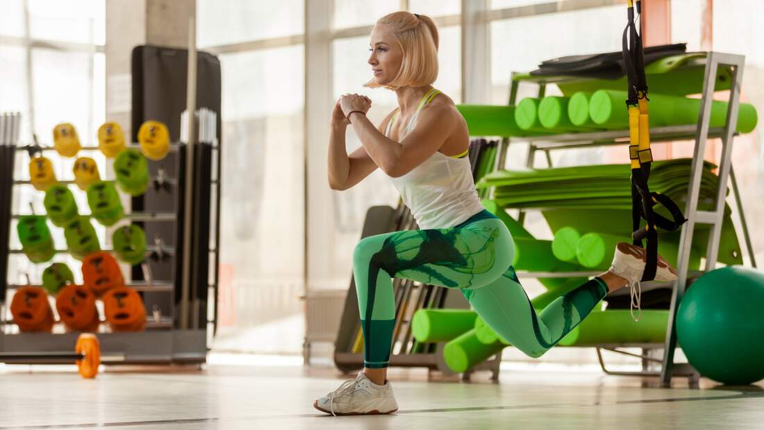 Frau macht Split Squat im Sling Trainer
