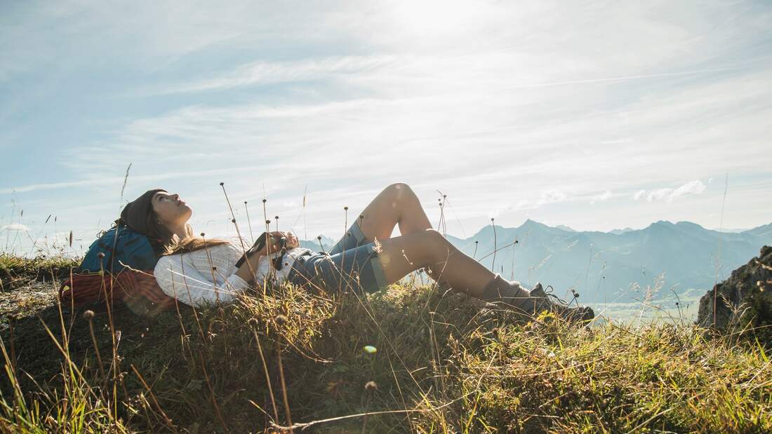 Frau macht beim Wandern eine Pause und liegt im Gras.