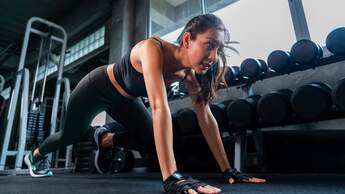 Frau macht eine Stützübung am Boden im Gym und schwitzt