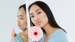 Frau neben Spiegel mit Blume