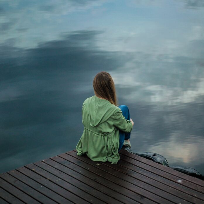 Frau sitzt an See
