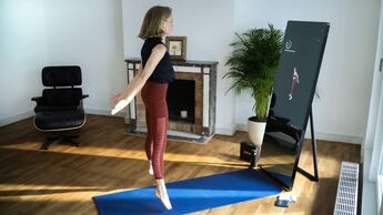 Frau trainiert vor einem digitalen Fitnessspiegel