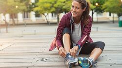 Mature,Fitness,Woman,Tie,Shoelaces,On,Road.,Cheerful,Runner,Sitting