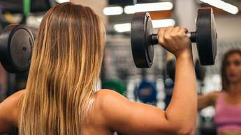 Nahaufnahme einer Frau von hinten mit starken Schultern beim Schulterdrücken.