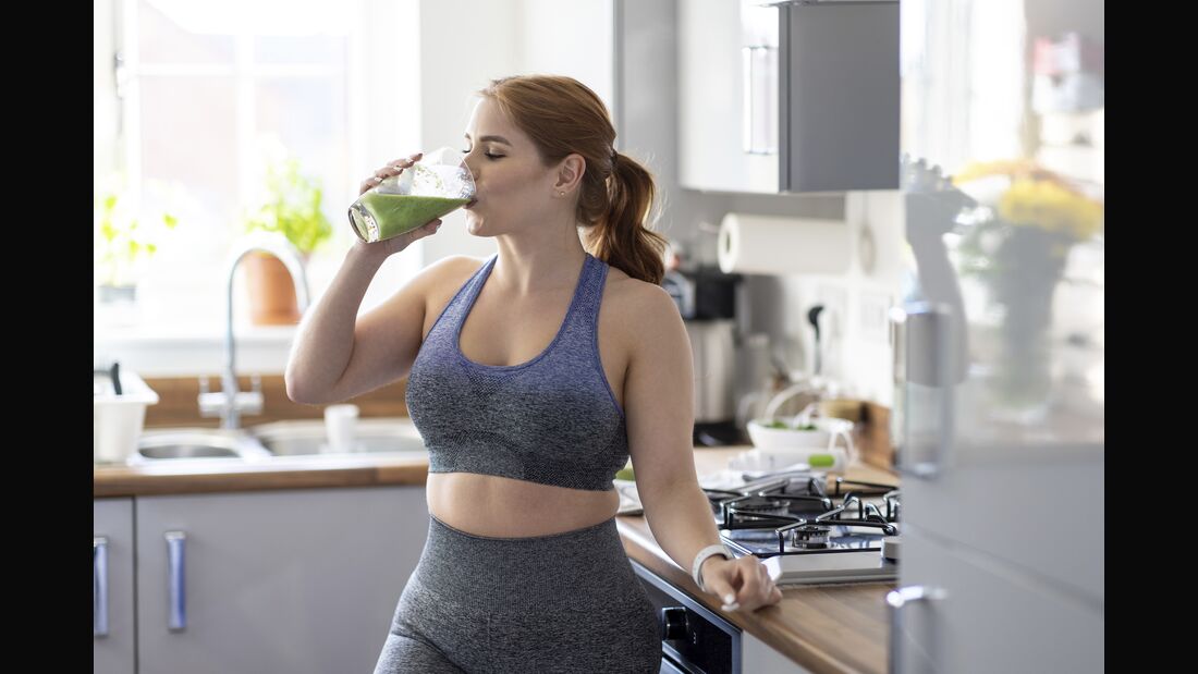 Redhead woman drinking healthy milkshake after working out at home