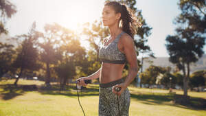 Trainierte Frau in Sport-BH springt bei Sonnenschein Seil