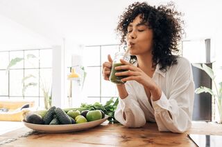 Young,African,American,Woman,Drinking,Green,Juice,With,Reusable,Bamboo