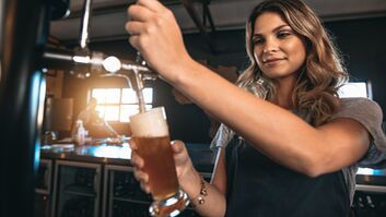 Young,Woman,Dispensing,Beer,In,A,Bar,From,Metal,Spigots.
