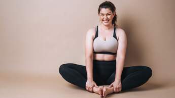 Zufriedene Frau mit Kurven im entspannten Yoga-Sitz.