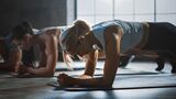 mehrere Frauen führen auf Yogamatten den Unterarmstütz aus